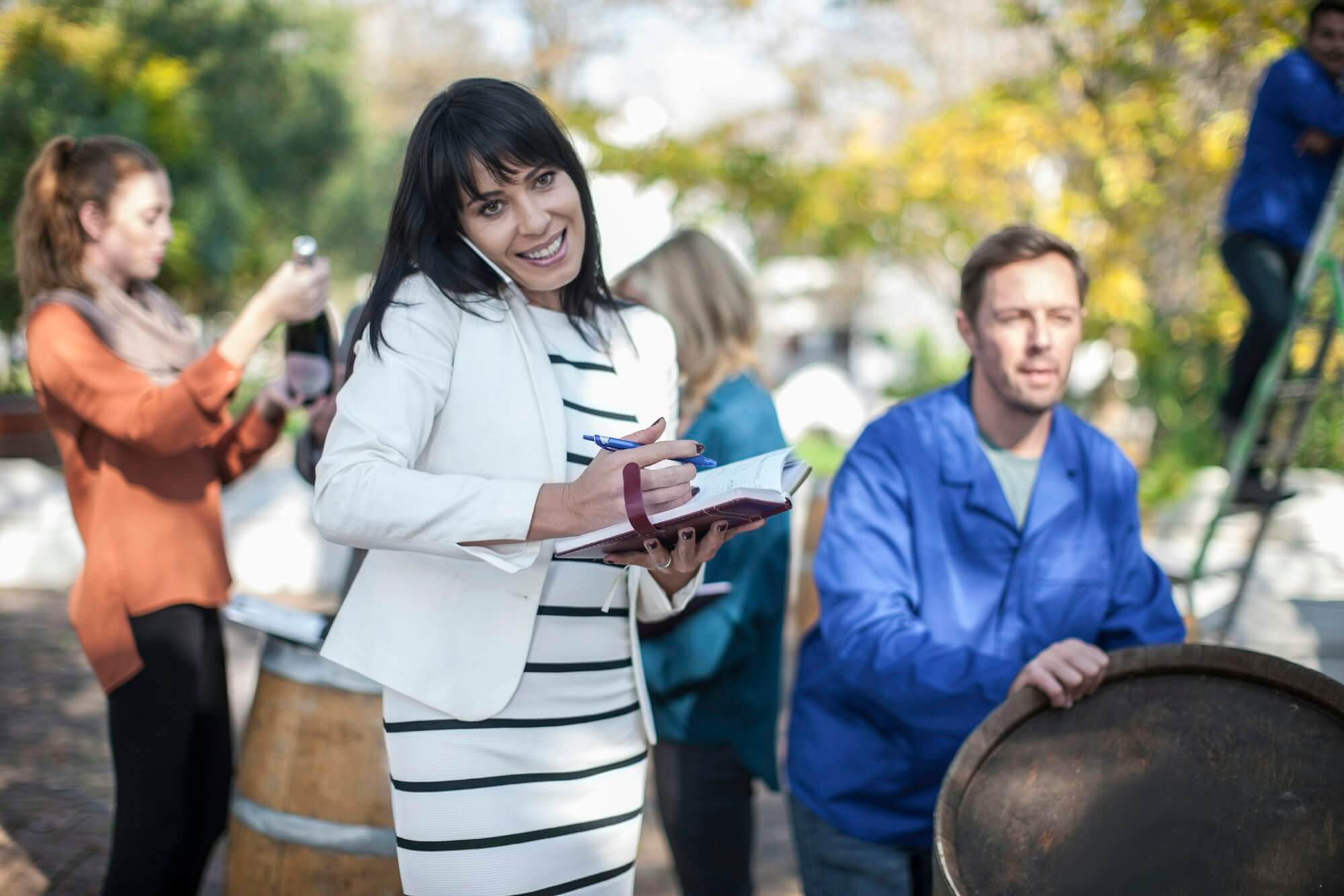 wine-saleswoman-with-group-of-clients-outdoors-and-wine-worker-with-barrel.jpg